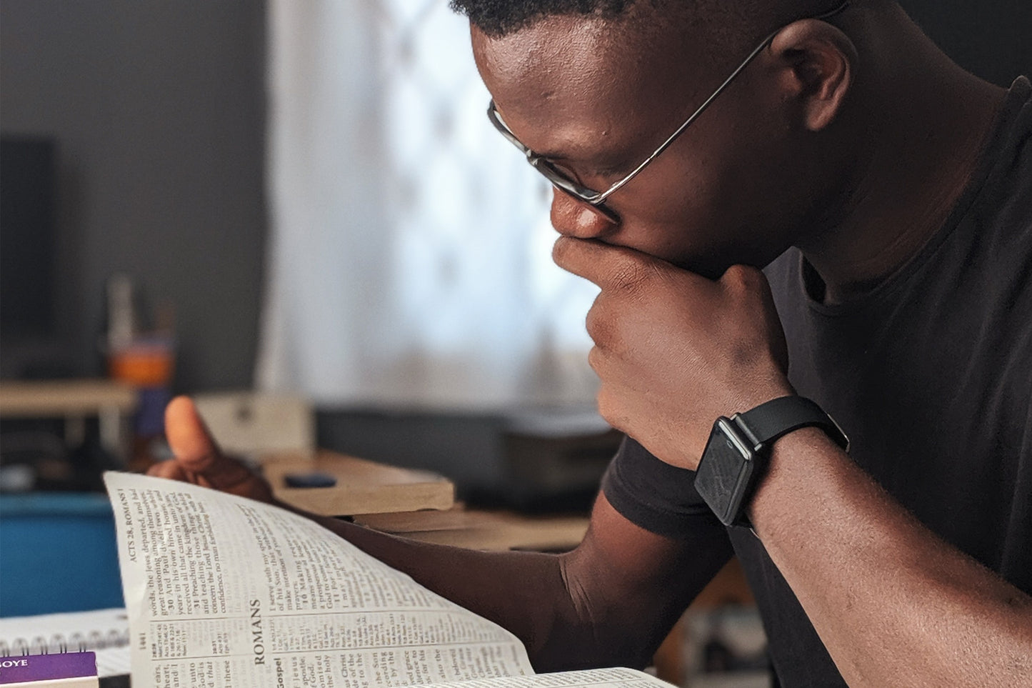 A boy reading through a book on desk