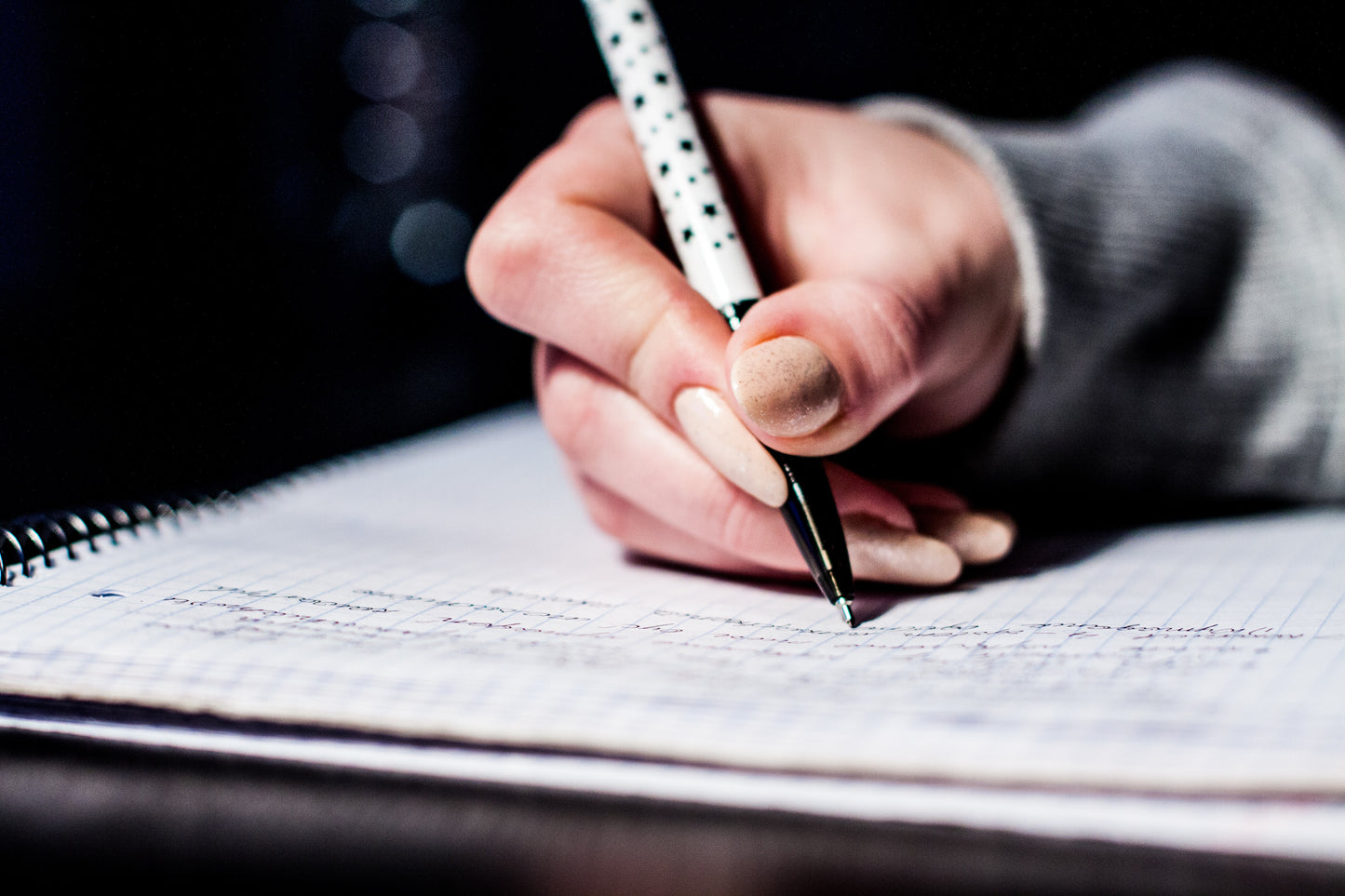 Hand holding a pencil writing on a piece of paper