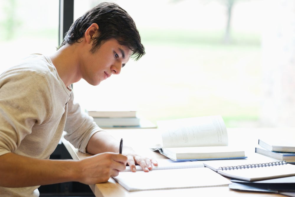 Student who is writing on page over a desk